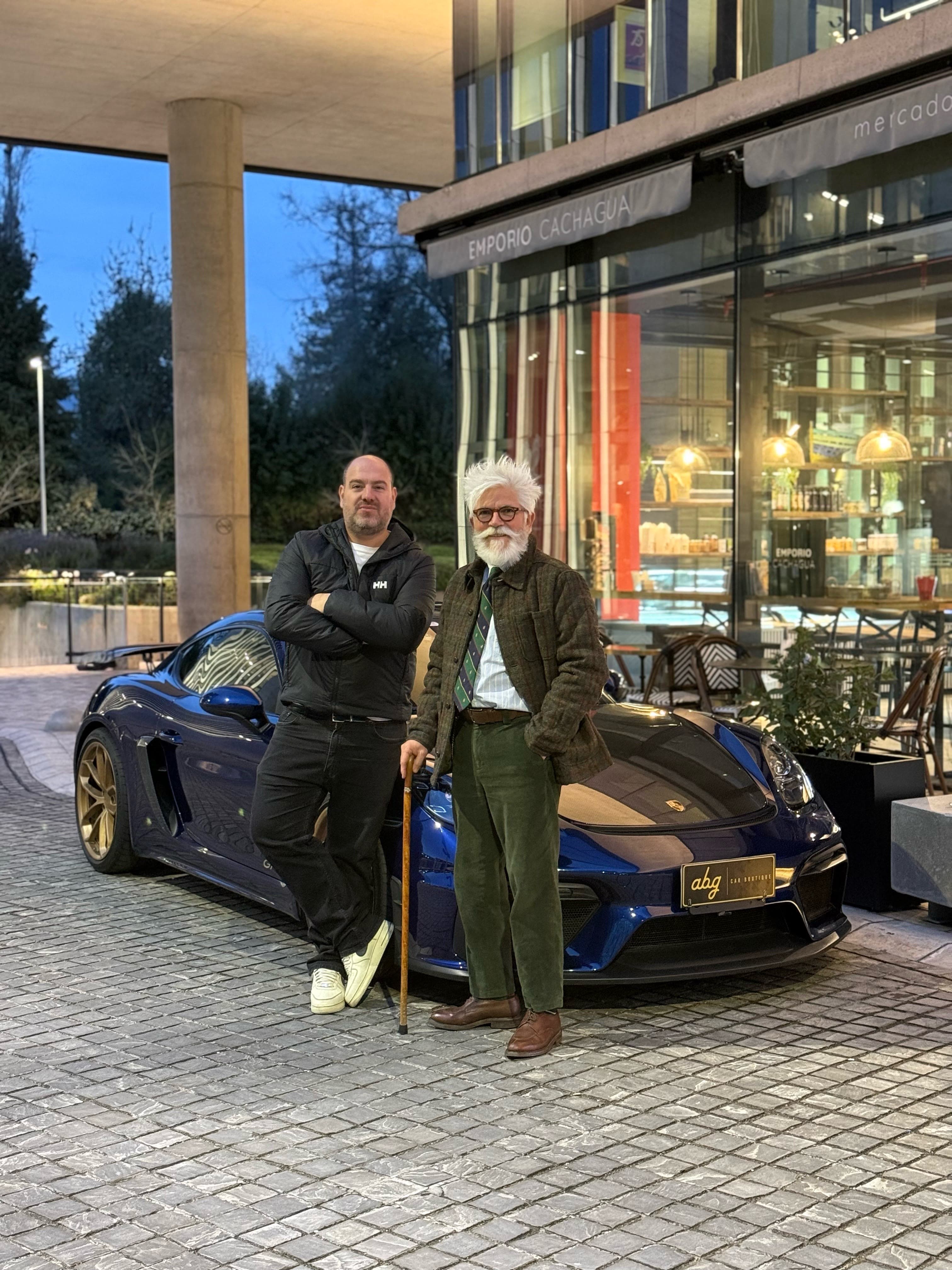 Dos integrantes de ABG Car Boutique junto a un Porsche azul